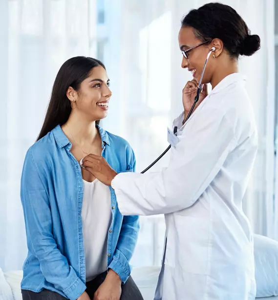 Médica auscultando o coração da paciente